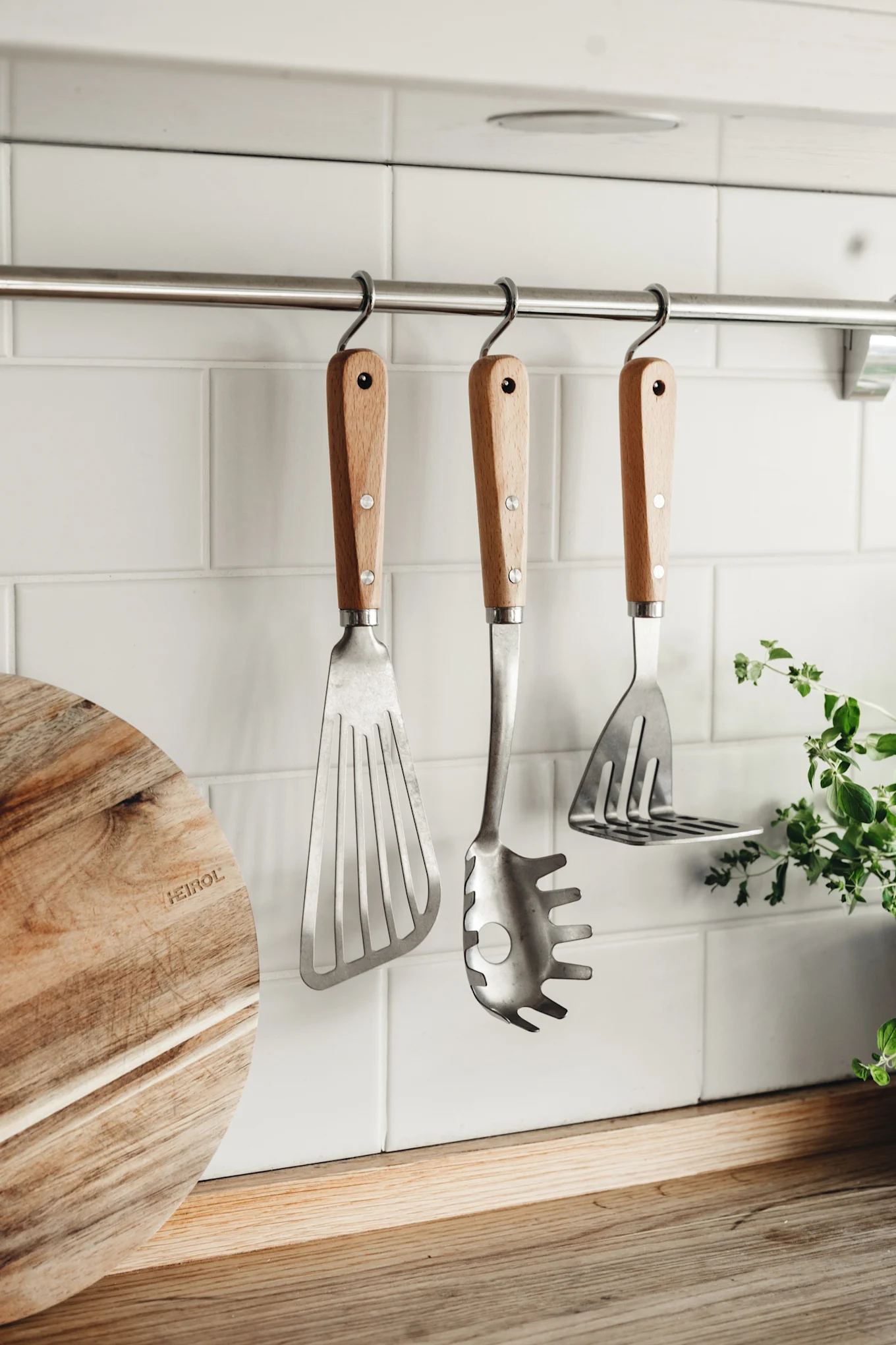 Heirol stekspade, slev och potatismosare hängande på en stång i köket.