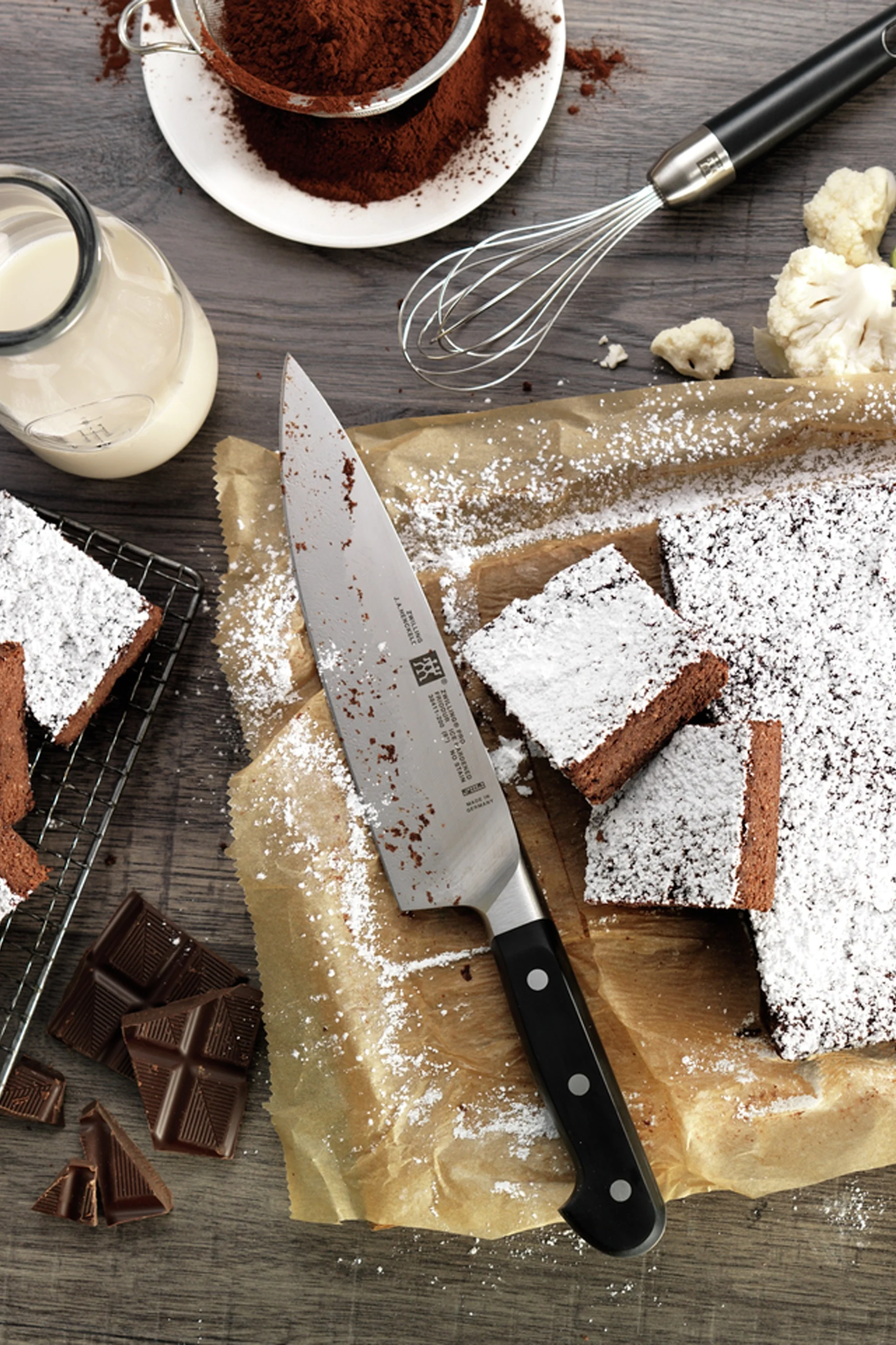 Kökskniven Pro från Zwilling ligger på ett bakplåtspapper med brownies.