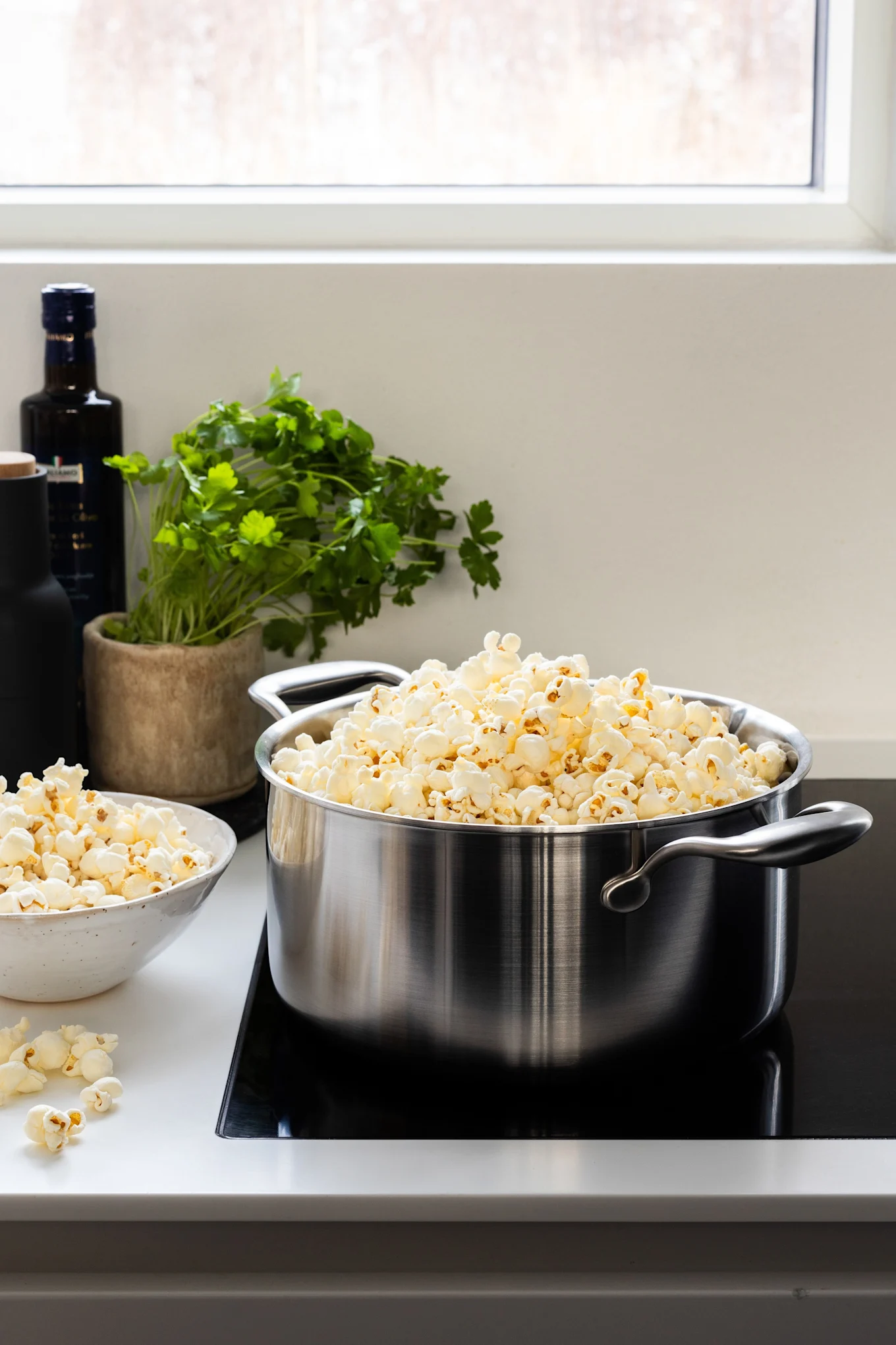 Kokgrytan med hälllock från Wilfa står på en häll med färdiggjorda popcorn.