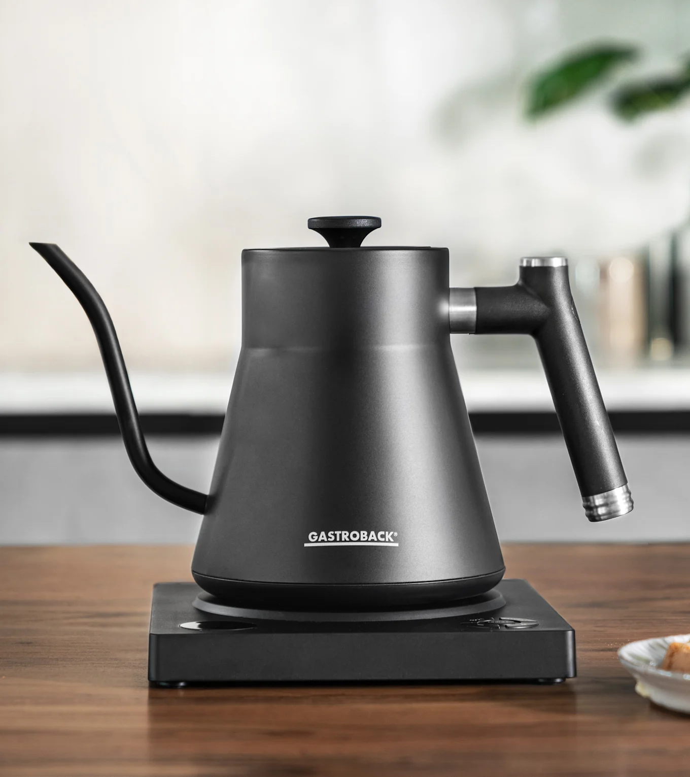 Matt svart pour-over vattenkokare med svanhals pip på en matchande elektrisk bas.