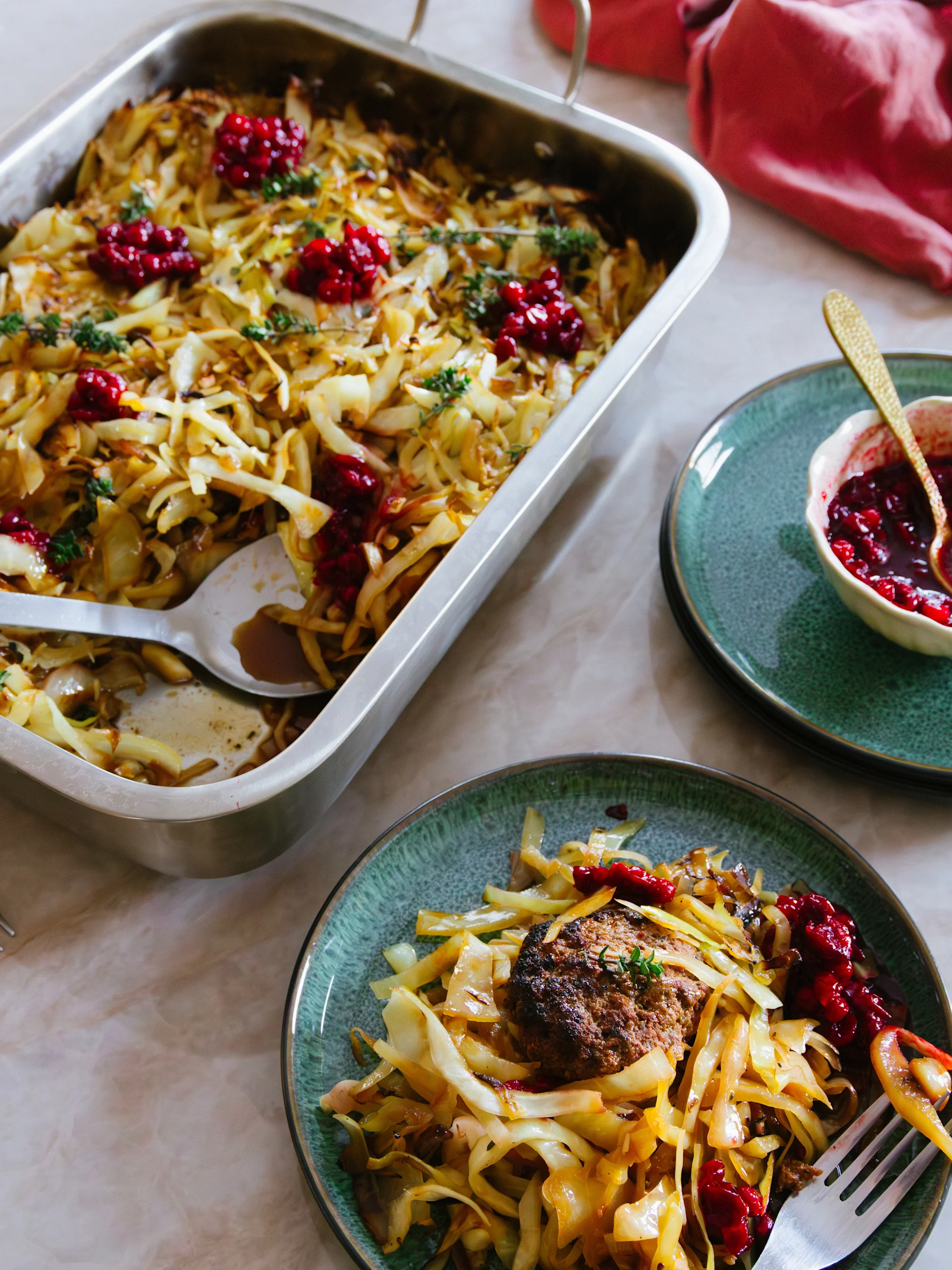 Kålgryta med köttbullar och lingonsylt, serverad från en metallform till en grön tallrik.