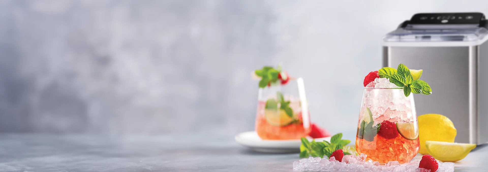 Uppfriskande hallondrinkar med krossad is, mynta, lime, bredvid en ismaskin och färska citroner.