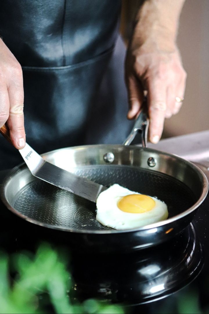 Någon steker ett ägg i en stekpanna av rostfritt stål med non stick-beläggning och bikakestruktur. 